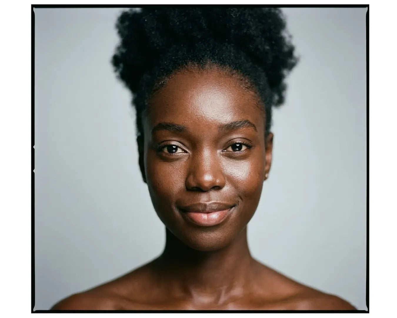 Beautiful black woman with bare shoulders and a gentle smile is looking into the camera