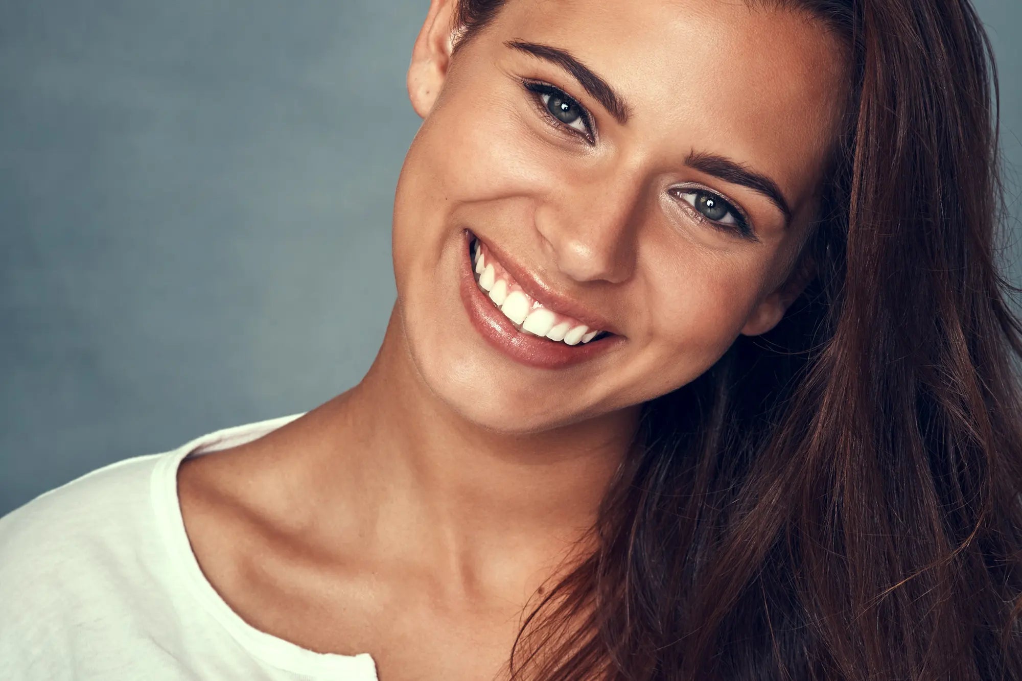 A woman smiling as she faces the camera with her head slightly titled to the right